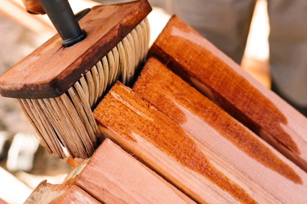 A large brush being used to stain wood.