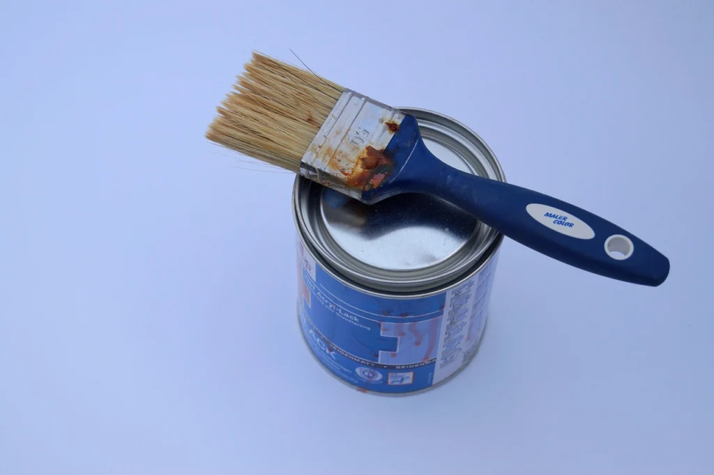 Paint can and paint brush with acrylic paint.