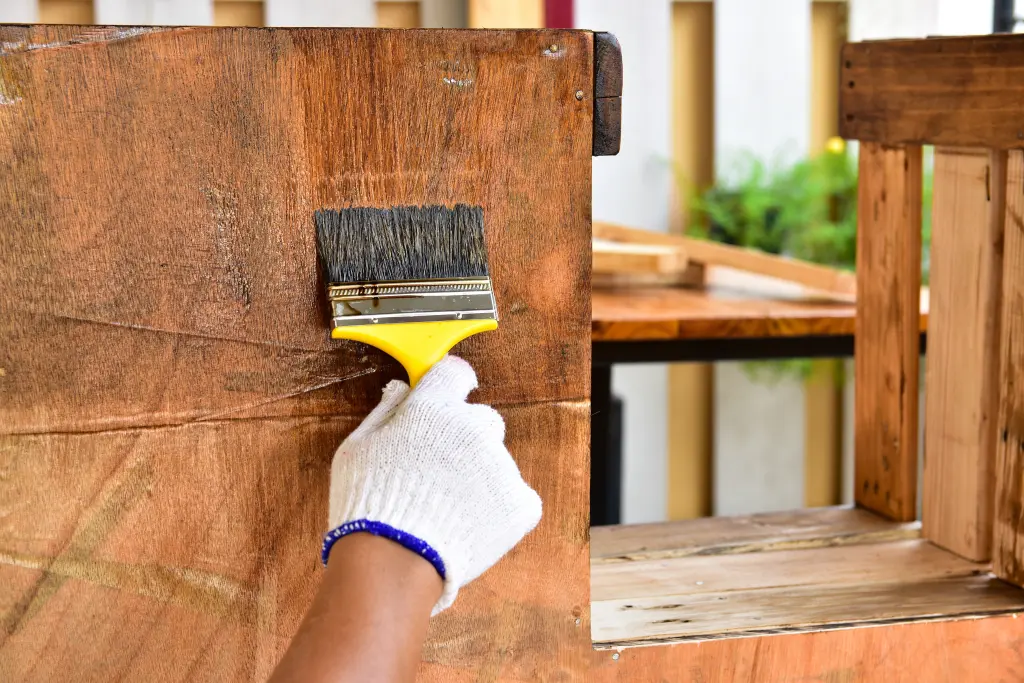 A gloved hand painting lacquer onto an interior surface.