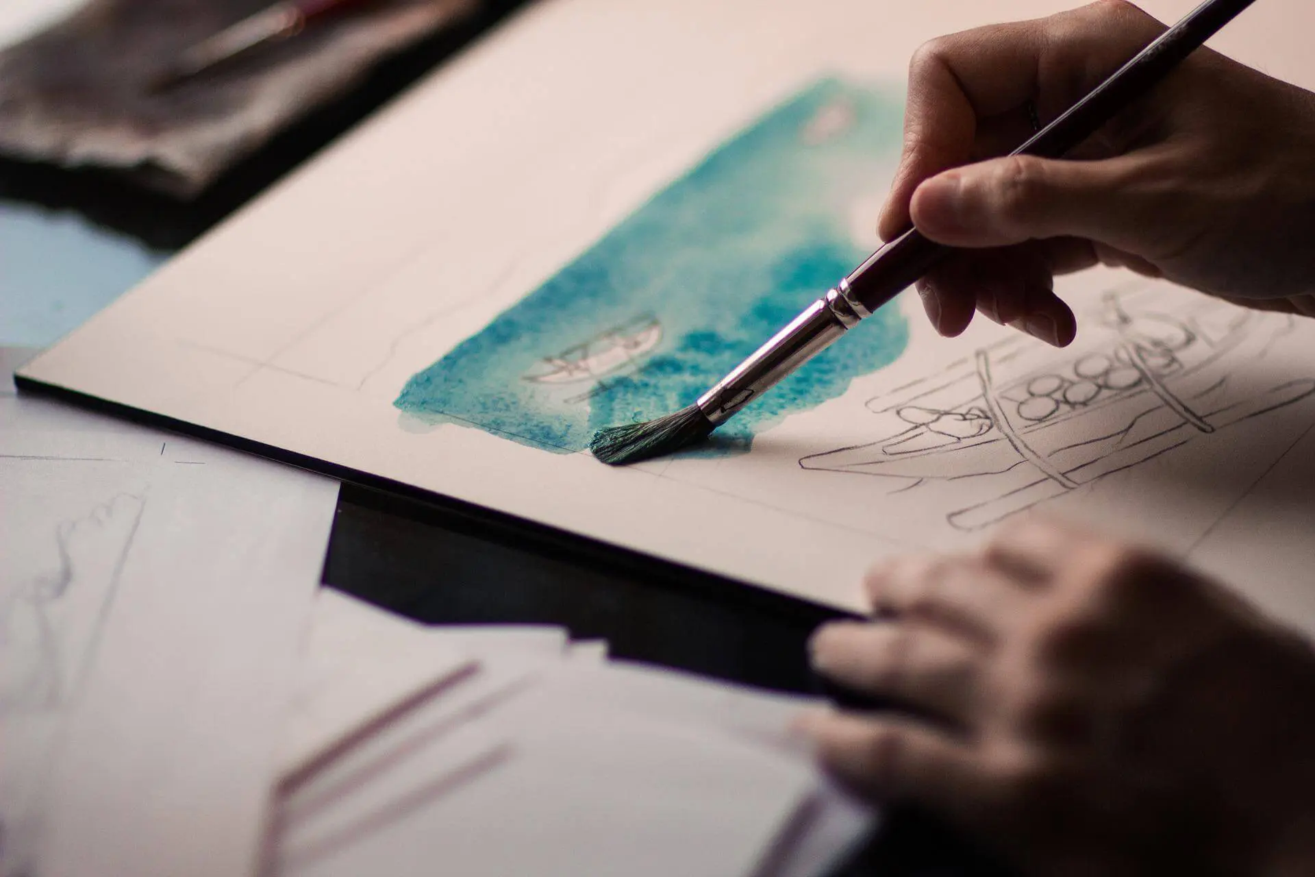 Hands painting a scene watercolors