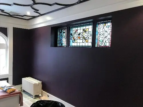 unnamed-1 A room with dark and deep purple walls, renovated ceiling with an interesting design and stained glass windows.