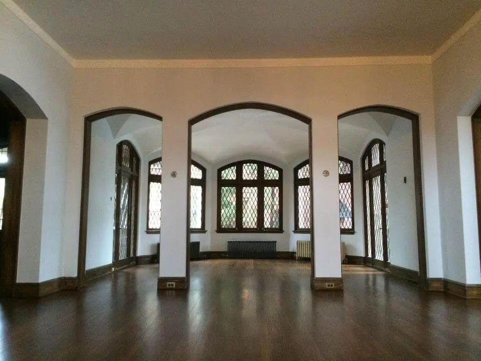 White painted walls with high archways in a large open space with exquisite curved windows and hardwood floors.