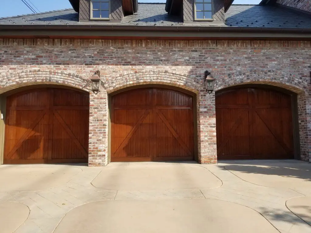 IMhoff-wood-restore-1-1024×768 Three wooden garage doors fully restored in the exterior of a red and gray brick home.