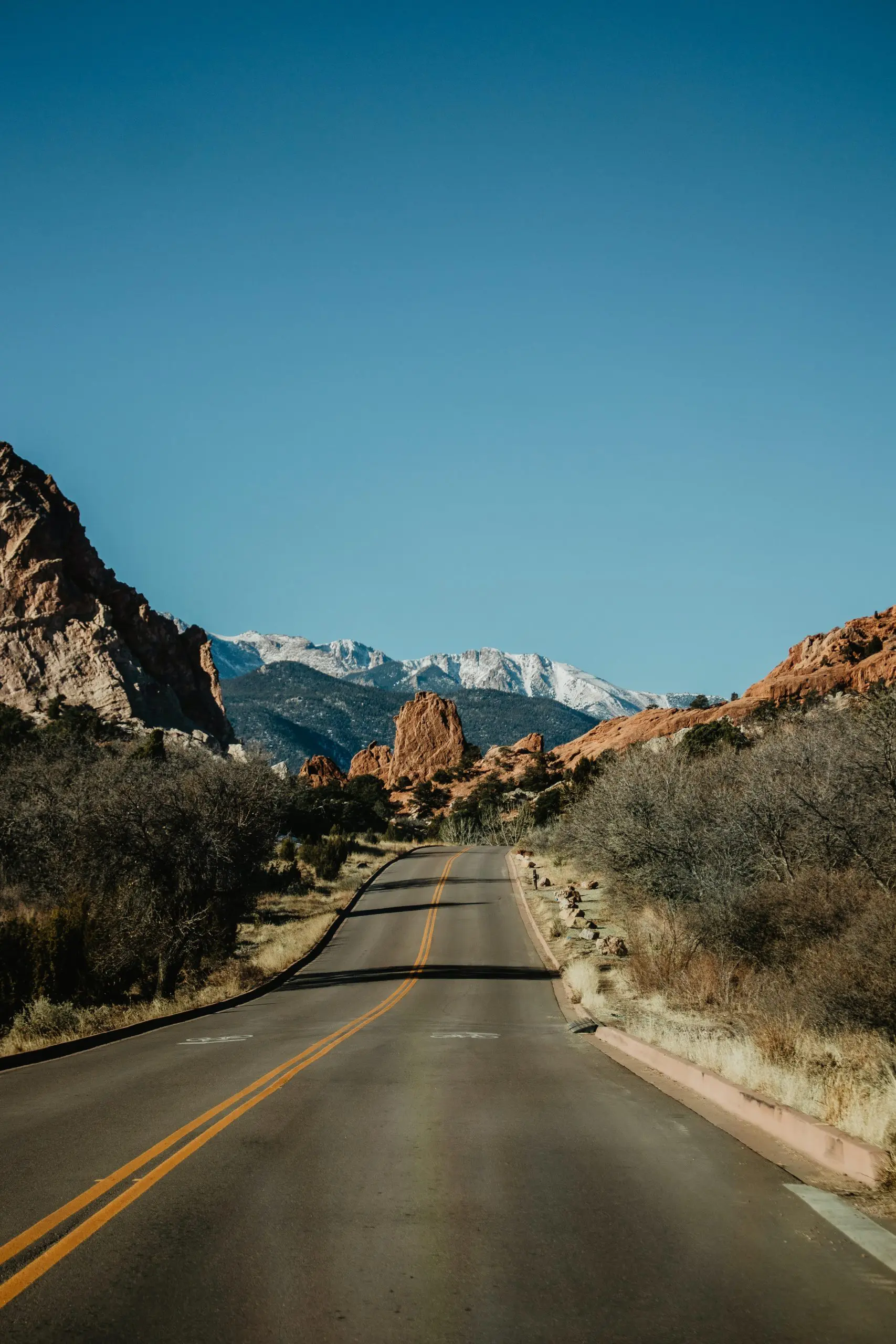 A road to drive down from the perspective of a car driving down the road with a nice mountain view ahead.