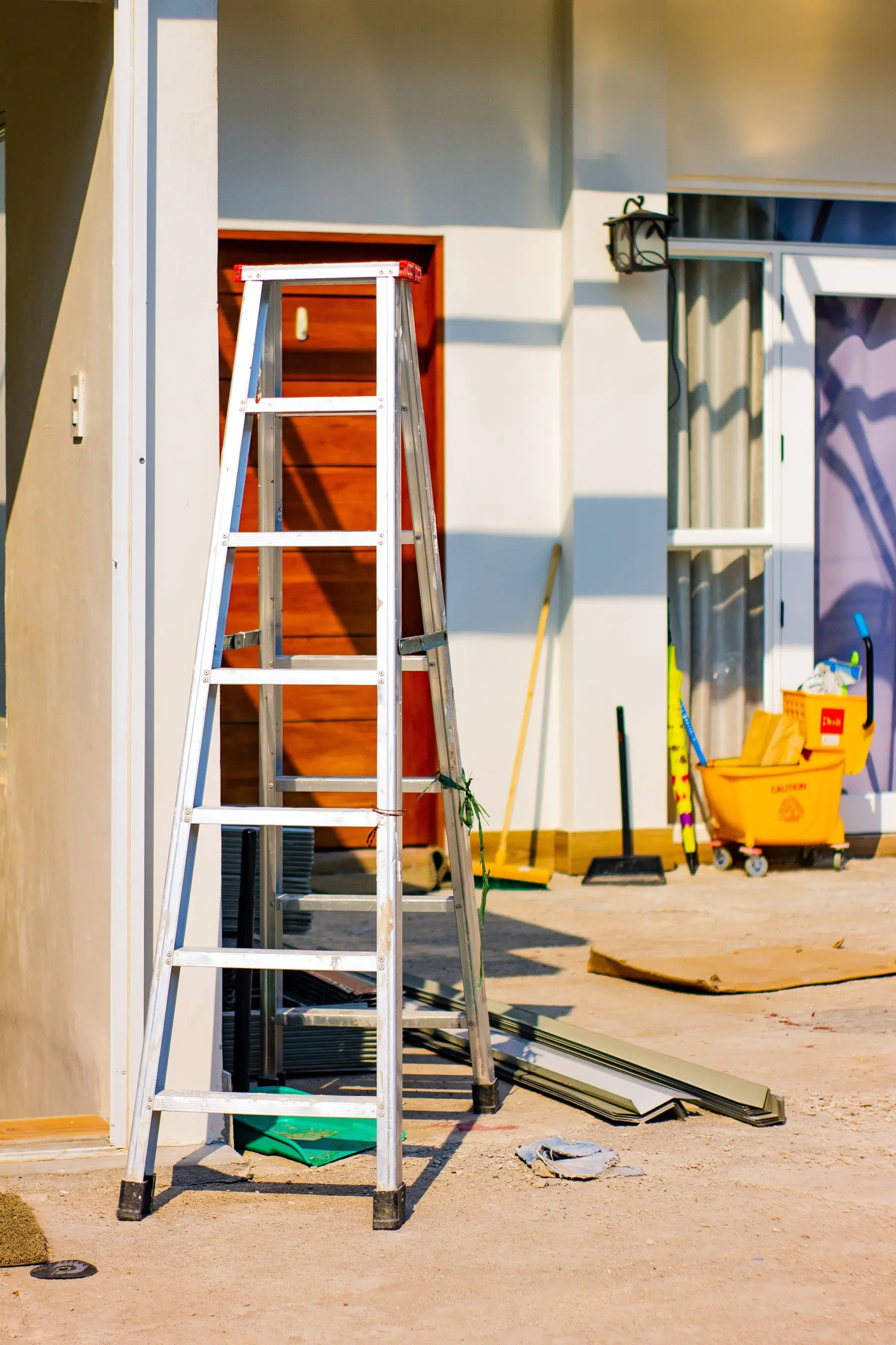 Here stands a ladder and some remodeling supplies outside of a building undergoing renovations.