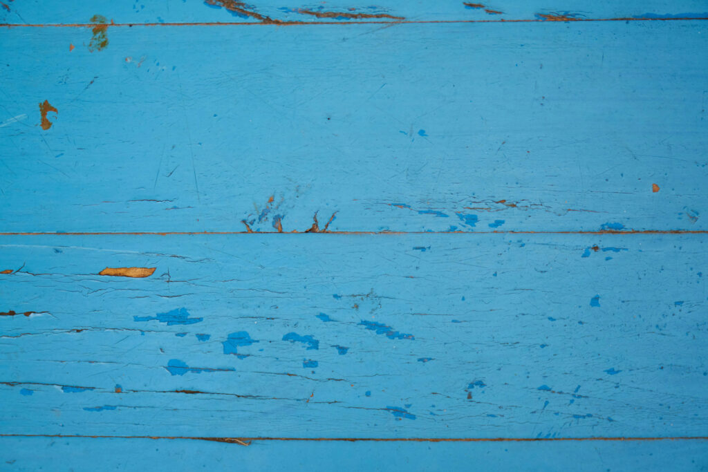Paint peeling and cracking on a blue wall.