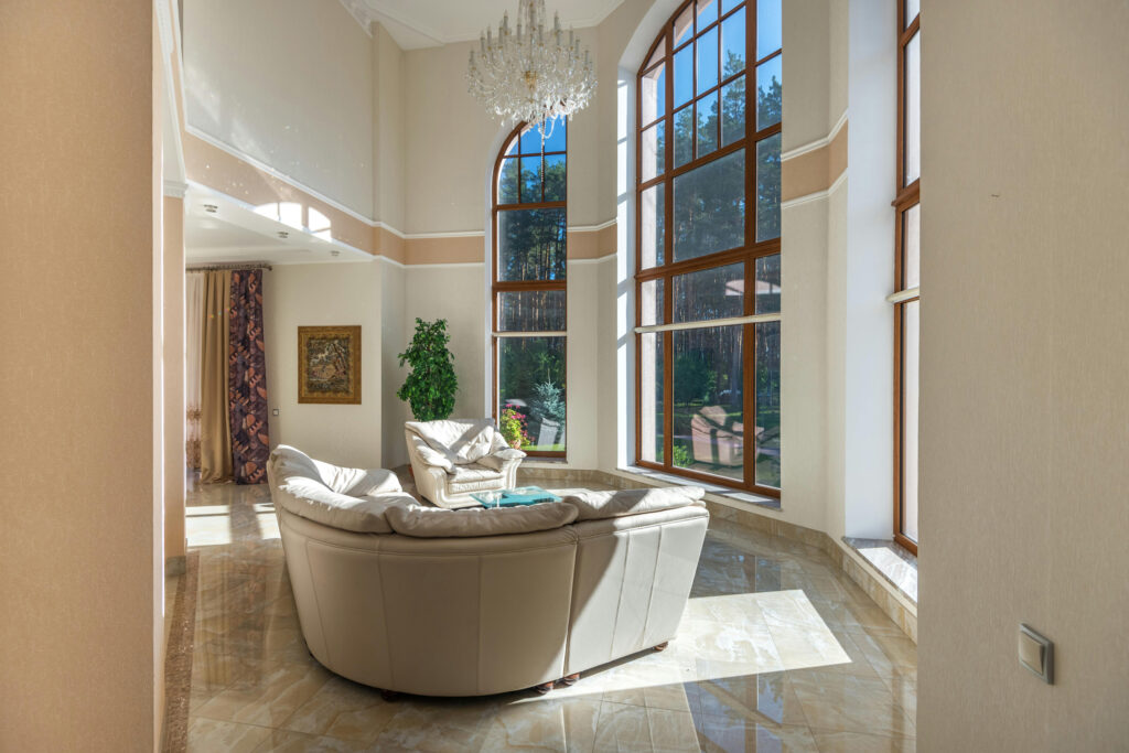 A living area with high ceilings, large windows and beige colored paint and trim.