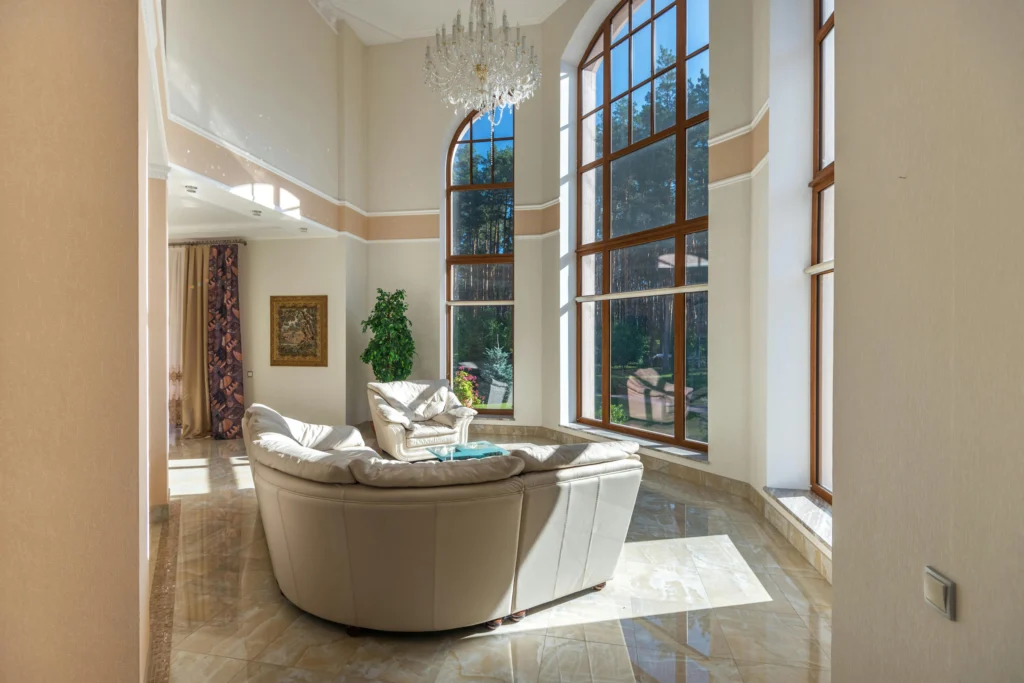 A living area with high ceilings, large windows and beige colored paint and trim.