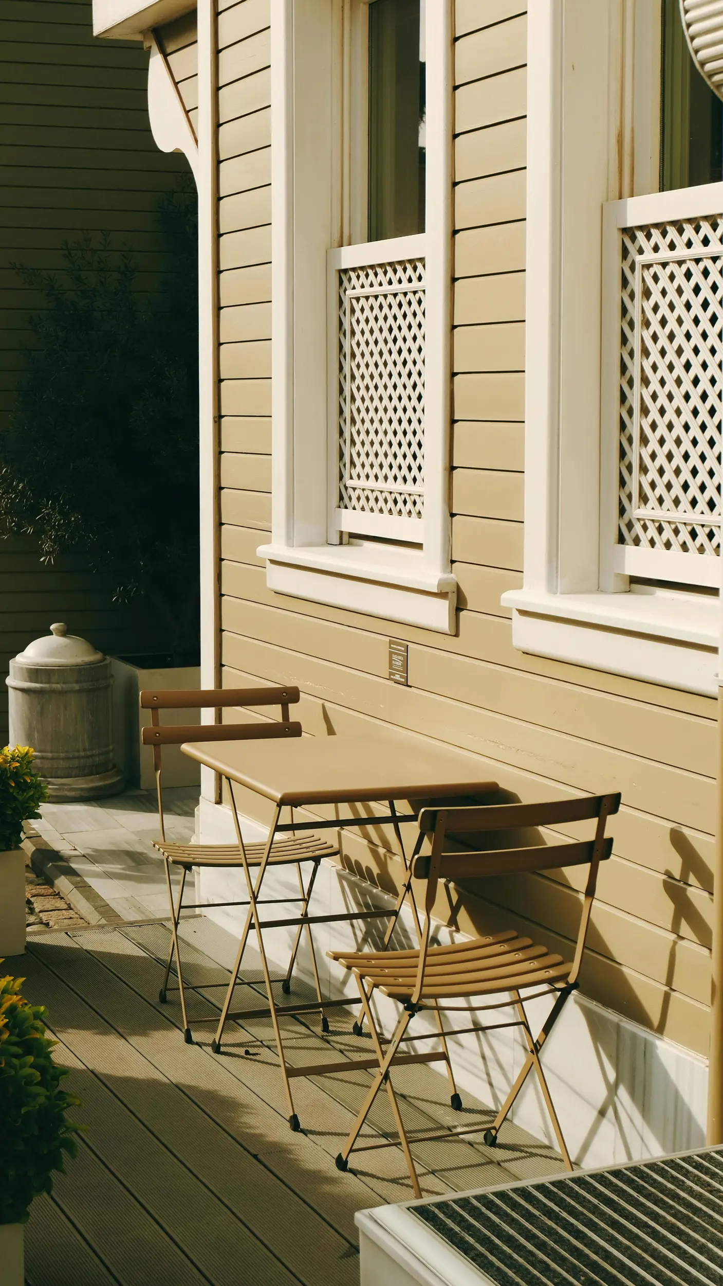 residential painting services in denver, co Tan exterior of a home with a table and two chairs outside on the porch.